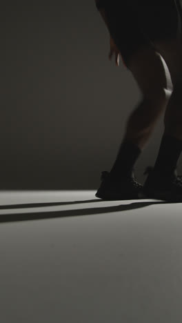 Vertical-Video-Close-Up-Side-View-Studio-Shot-Of-Male-Basketball-Player-Running-Jumping-And-Shooting-Ball-At-Basket